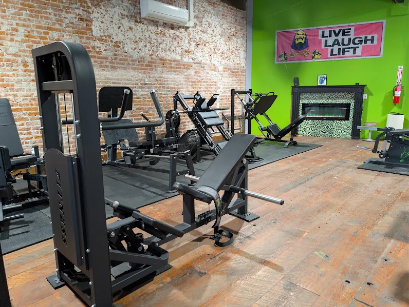 Plate-loaded hip thrust machine beside lower-body equipment at Hero Lab.
